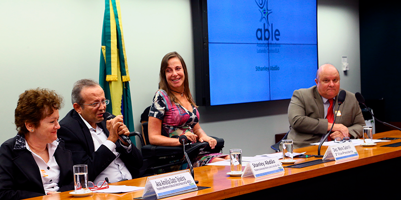 Mara, no centro da mesa do evento. Do lado esquerdo está Stanley Abdão e Ana Amélia Teixeira. Ao fundo um painel com o logo da Able.